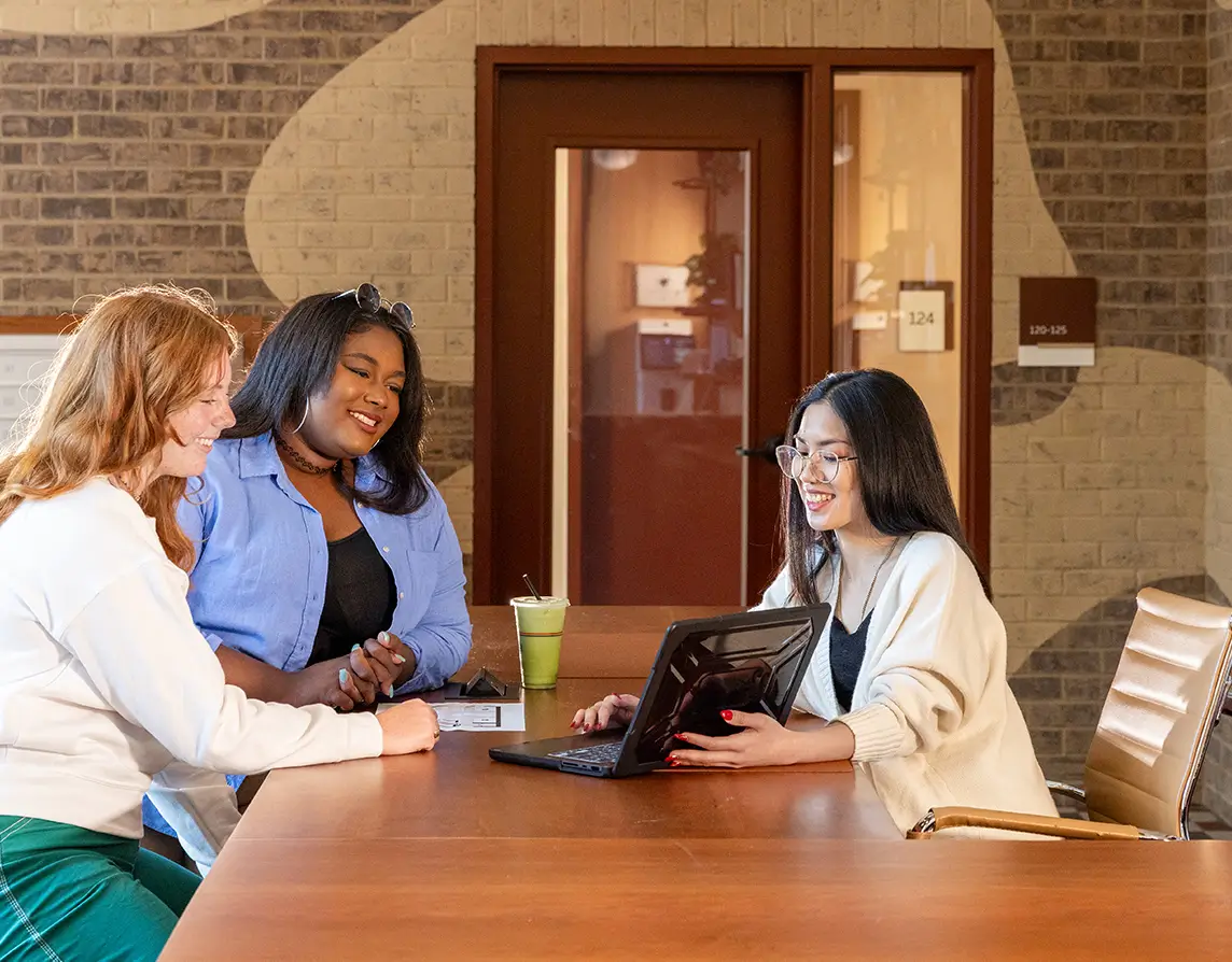 a group of people looking at a laptop